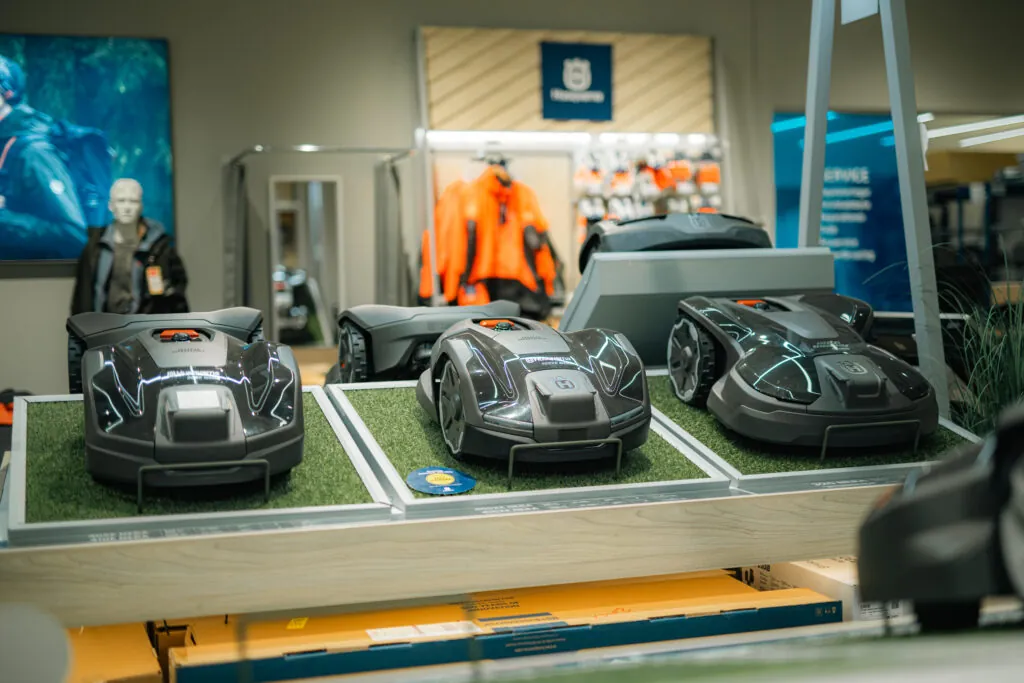 Fyra Husqvarna robotgräsklippare i svart och grått utställda på konstgräs i butiksdisplay